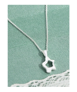 Close-up of a silver hollow star pendant necklace on a dark green textured background