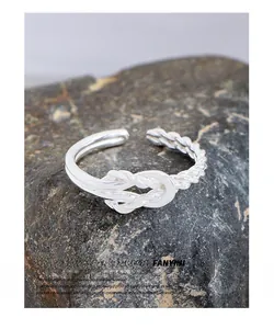Detail of S925 sterling silver twisted rope knot ring on dark natural stone texture