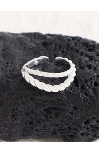 Macro shot of double-layered twisted silver ring on black rock with woven texture detail