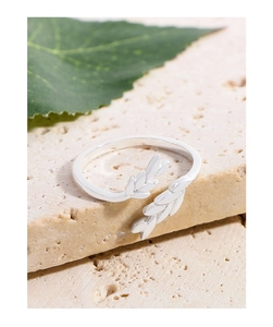 Macro shot of silver wheat leaf ring on stone base with a green leaf background