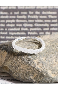 Macro shot of twisted silver rope ring on stone surface with a vintage background