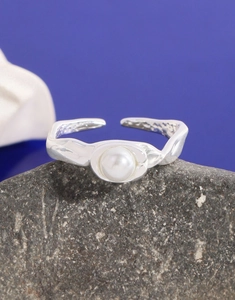 Makroaufnahme eines unregelmäßigen S925 Silberrings mit Perle auf grauem Stein