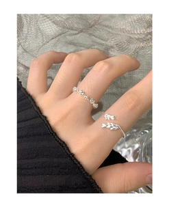 Detailed view of silver wheat leaf open ring set worn on finger with mesh background
