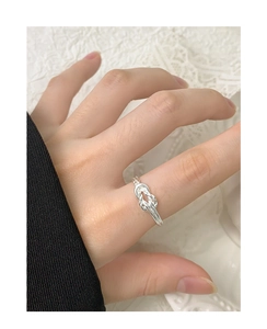 Detailed close-up of S925 sterling silver twisted knot ring on finger with lace background