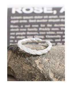 Macro detail of silver twisted rope ring placed on natural stone for textured jewelry display