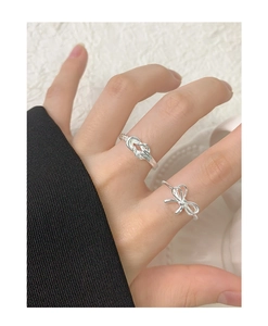 Close-up of S925 silver rings set with bow and twist knot designs on female fingers