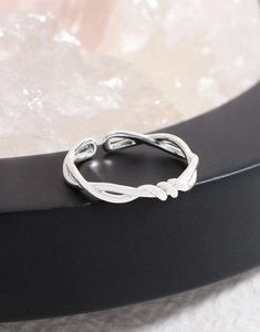 Macro detail of silver S925 adjustable open ring with intricate twisted line cross design