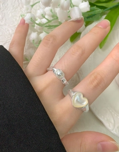 Dettaglio anello a cuore in argento con intarsio in conchiglia e perla sulla mano