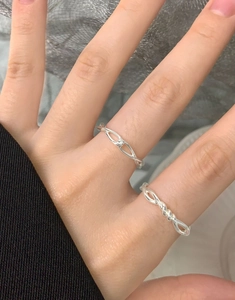Detailed macro view of S925 sterling silver hollow chain and twisted rope rings on a finger