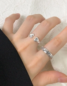 Detail of silver S925 rings featuring a double heart open design and engraved star patterns