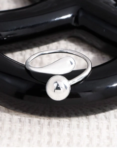 Macro shot of polished silver geometric ring with spherical and teardrop elements