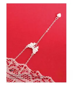 Macro shot of silver bow heart pendant necklace on red background with white lace detail