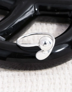 Macro shot of silver S925 ring featuring a polished geometric sphere and abstract curved design