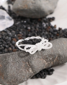 Macro shot of silver bow knot ring on natural stone showing twisted rope texture detail