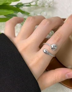 Macro shot of silver geometric ring with teardrop and sphere design on a hand