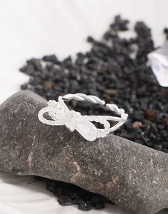 Detailed close-up of S925 sterling silver bow ring with twisted band on dark stones