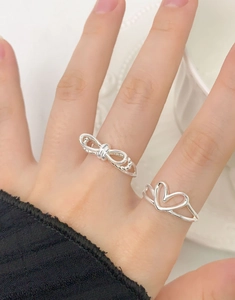 Close-up of S925 silver double-layered twist bow and hollow heart rings on a hand