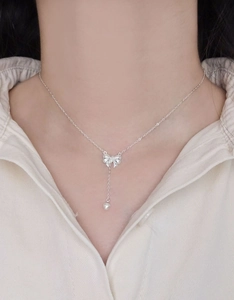Close-up of S925 sterling silver bow necklace with heart pendant on model