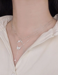 Close-up of elegant double-layered S925 silver necklace with ribbon bow and heart pendant