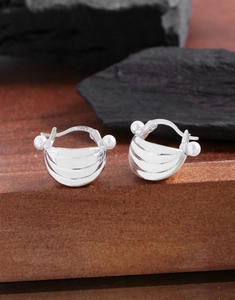 Macro detail of S925 sterling silver hoop earrings with white pearls on a wood base