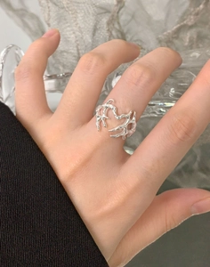 Dettaglio dell'anello a cuore in argento con texture lava fluida sulla mano