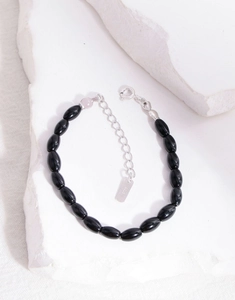 Macro shot of S925 sterling silver tag and black agate beads on a white stone base