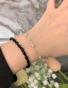 Close-up of minimalist S925 silver beaded bracelet and black onyx stone bangles on wrist