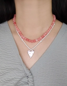 Detail of a double-layer necklace with pink agate beads and a polished heart pendant