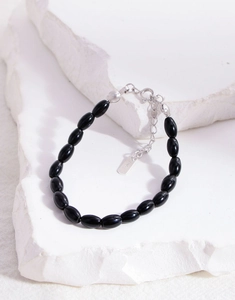 Macro shot of S925 sterling silver clasp and oval black onyx beads on white stone