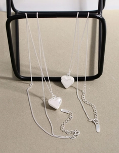 Detailed view of S925 sterling silver long heart pendant necklaces on a display stand