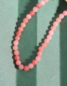 Macro shot of natural pink agate beads on a dark green textured background with soft lighting