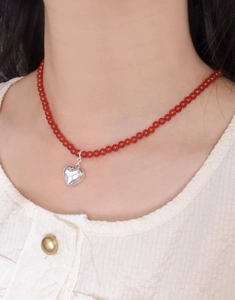 Gros plan du collier en perles d'agate rouge avec pendentif cœur en argent sur mannequin