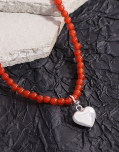 Détail macro du collier de perles en cornaline rouge avec pendentif cœur argenté