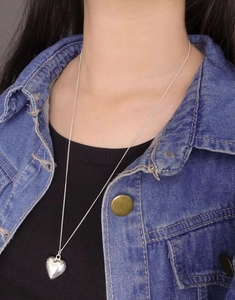 Close-up of a glossy 3D heart pendant on a fine S925 silver chain worn by a model