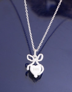 Macro detail of S925 sterling silver stamp on heart moonstone bow pendant necklace