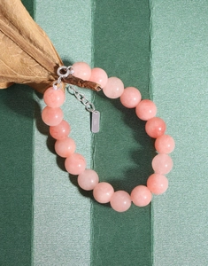 Detail of pink agate beaded bracelet with S925 sterling silver clasp on dark green base