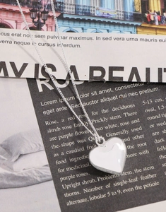 Macro detail of a 925 sterling silver heart locket necklace on a newspaper background