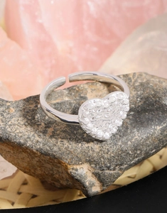 Macro shot of silver heart ring with embossed lava texture on a natural stone background