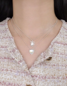 Detailed view of layered 925 silver necklace with bow and moonstone heart pendants
