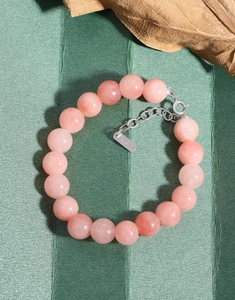 Close-up of S925 sterling silver clasp and pink agate beads on a textured surface