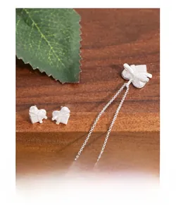 Détails d'un ensemble de bijoux cœur et nœud papillon en argent S925 sur bois naturel