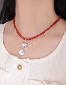 Gros plan du collier double épaisseur en argent S925 avec perles rouges et pendentif cœur
