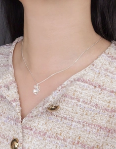 Detail of S925 silver bow necklace with heart moonstone pendant on a female model neck