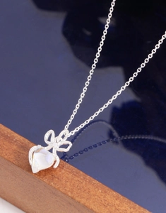 Macro shot of silver bow pendant with heart-shaped moonstone on a dark blue surface