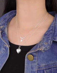 Detailed view of layered S925 sterling silver necklace with solid and hollow heart pendants