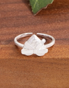 Macro shot of silver bow heart ring with embossed texture on natural wood and leaf
