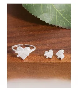 Détail de boucles d'oreilles cœur en argent S925 et bague réglable sur support en bois