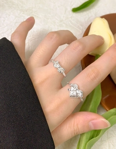 Detail of S925 sterling silver bow and heart rings stacked on a model's hand