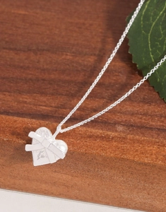 Détail du collier cœur en argent S925 avec ruban embossé sur fond de bois
