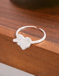Detailed view of S925 silver heart ring with bow relief and hammered metal texture
